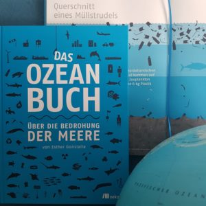 Das Ozeanbuch - Über die Bedrohung der Meere liiegt aufgesclagen, als auch mit dem Cover vor einem Globus