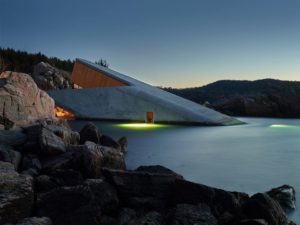 Außenansicht eines Unterwasserrestaurants, bei dem ein Ende in die Luft und das andere Ende ins Wasser ragt.