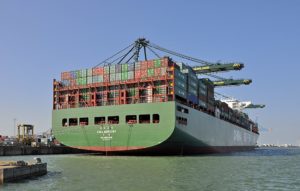 Ein großes, vollgeladenes Containerschiff liegt in einem Hafen an