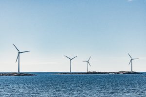 Vier Windräder stehen im Wasser an der Küste