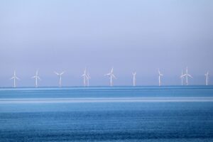 In der Ferne sieht man einige Windräder im Meer. Der Himmel hebt sich etwas dunkler vom Wasser ab.